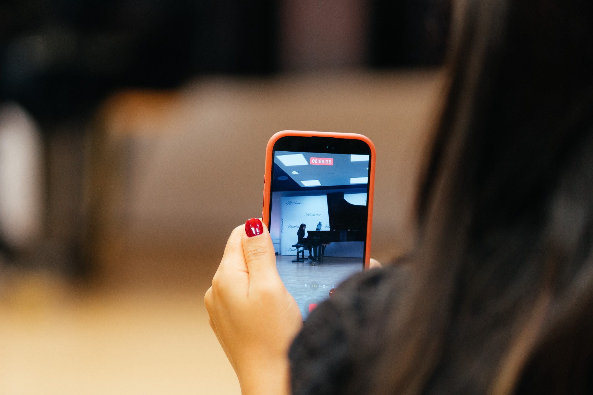 Audience member recording a student piano performance
